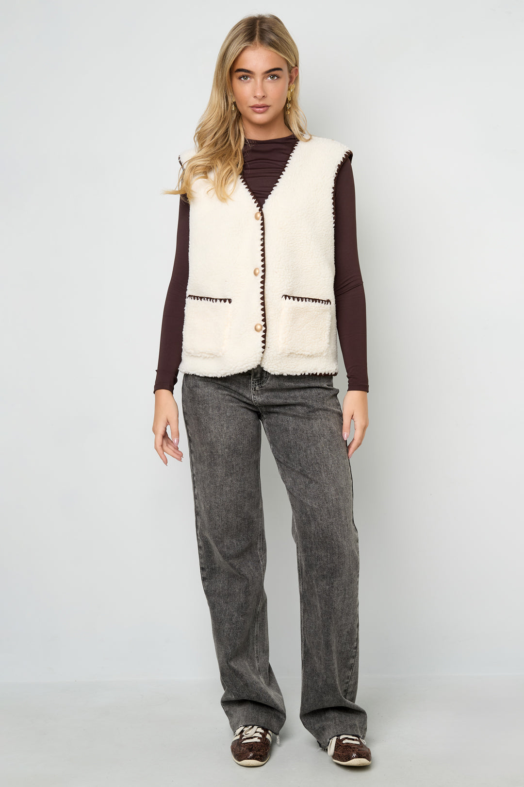 Vrouw draagt wit beige mouwloos vest met bruine details
