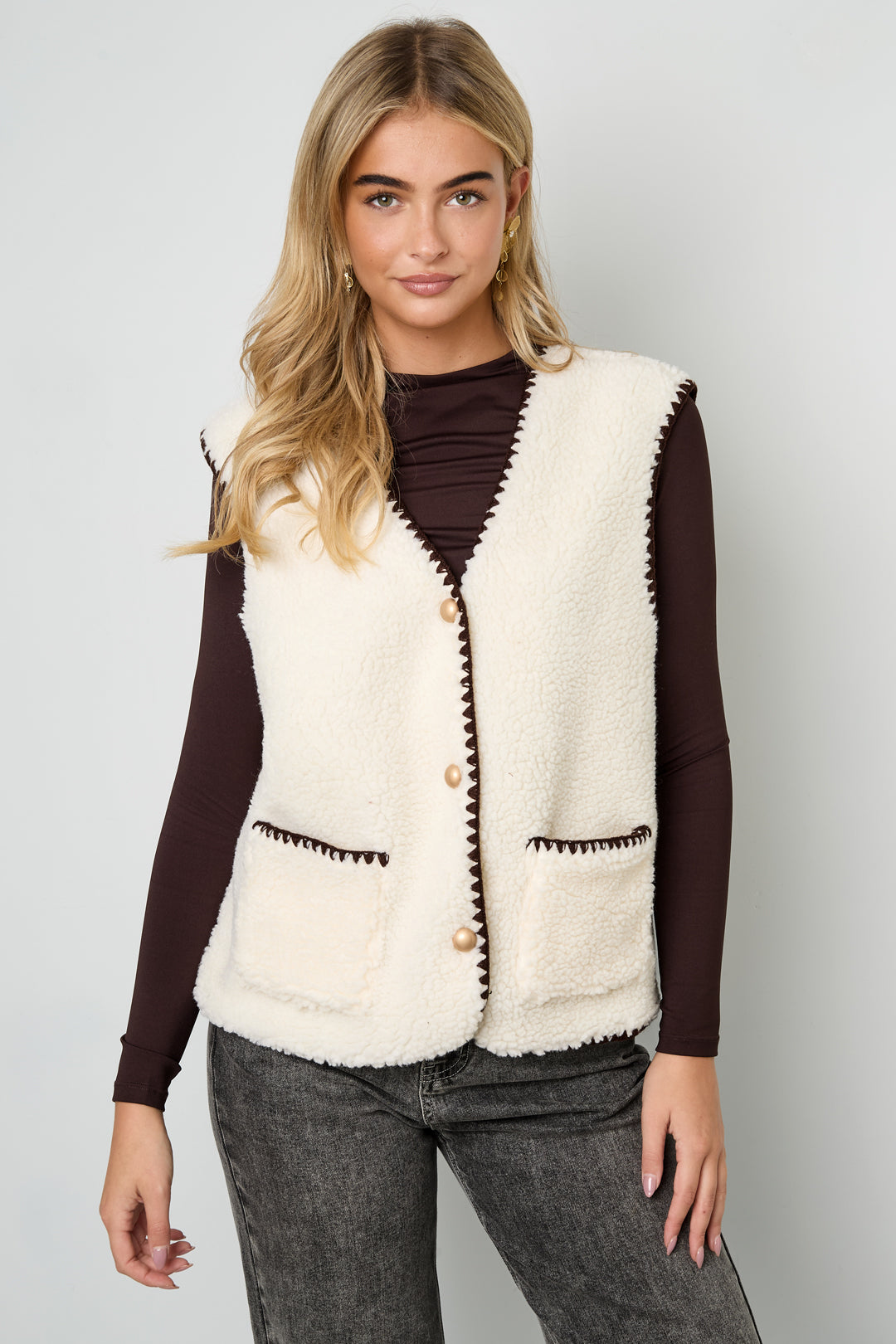 Vrouw draagt wit beige mouwloos vest met bruine details