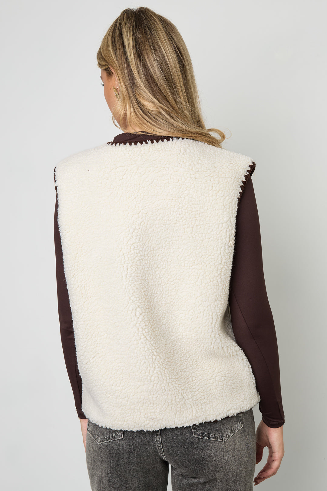 Vrouw draagt wit beige mouwloos vest met donkerbruine details