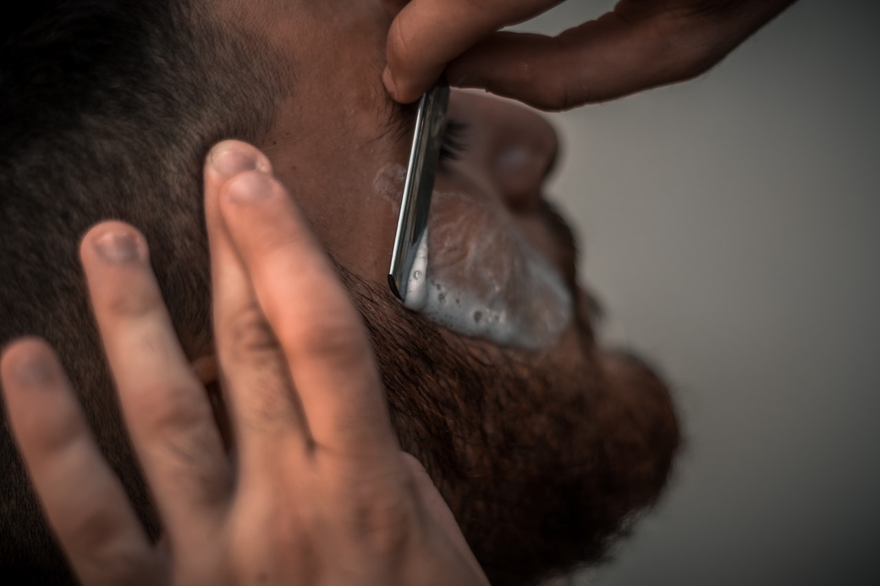 De barbier werkt een baard bij met een open scheermes